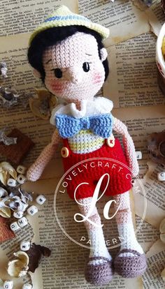 a crocheted doll sitting on top of an open book next to other items