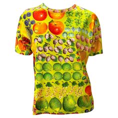 Presenting a vibrantly printed green t-shirt designed by Tom Ford for Gucci's Spring/Summer 1996 collection. The fruit print features the Gucci signature cleverly placed as stickers on the fruit. This rare and collectible shirt references Gucci's printed scarves. Approximate measurements: Size - M Bust: 42” Waist: 38” Shoulder to hem: 23.5” 100% cotton Green Digital Print Top For Summer, Casual Green Tops With Digital Print, Green Graphic Tee With Fruit Print, Green Short Sleeve Top With Fruit Print, Gucci By Tom Ford, Printed Scarves, Gucci Spring, Green T Shirt, Fruit Print