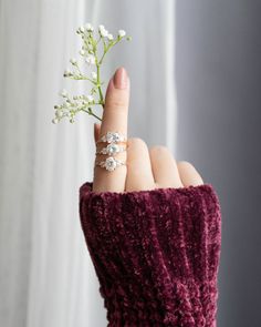 a woman's hand holding a tiny flower in her left hand and wearing a knitted sweater