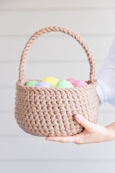 a person holding a crocheted basket with colored eggs in it and text overlay that reads, free crochet pattern for easter basket