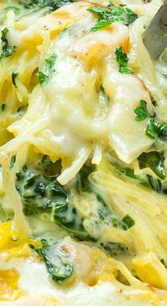 a casserole dish with spinach, cheese and chicken is being lifted by a spatula