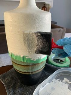 a white vase sitting on top of a table next to a pair of blue gloves