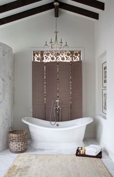 a white bath tub sitting under a window next to a rug