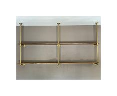 three brass shelves are hanging on the wall, and one shelf has two bars attached to it