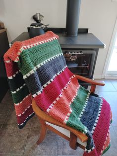 a chair with a blanket on top of it in front of a wood burning stove