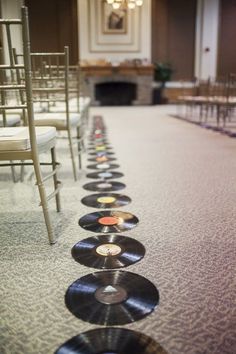 rows of vinyl records line the floor in front of chairs at a wedding ceremony,