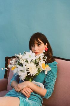 a woman sitting on a couch with flowers in her lap