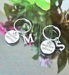 two silver key chains with charms attached to them sitting on top of a flower pot