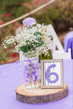 the table is set up with flowers in mason jars and a number six sign on it