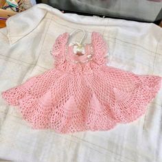 Super cute handmade by the private estate .... crochet dress.  Color is light pink with light green ribbon, white buttons and a white & pink bunny accent piece.  This is a vintage dress form the 1990's. My grandmother was a maker and made this dress for my future daughter....she hoped. I did have a daughter who wore but she never got to see it on her.   It was used a couple times.  Excellent condition but please do not expect it to be perfect.   No notable flaws I can see.  It has been packed away for over 22 years so it should be gently cleaned or professionally cleaned if you choose. Measurements are approximately --14 inches Shoulder to bottom --7 inches Pit to pit --3 inches Neck to neck I do not know the size in months or years as it was made at home by hand.   Please be sure to inspe Cute Lace Baptism Dress, Pink Lace Dresses With Crochet Trim, Pink Lace Dress With Crochet Trim, Cute Handmade Dress For Baptism, Cute Handmade Pink Dress, Cute Hand Knitted Pink Dress, Handmade Pink Crochet Dress In Cute Style, Handmade Pink Crochet Dress Cute Style, Cute Pink Crochet Dress For Summer