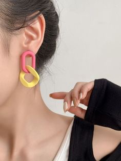 a woman wearing pink and yellow earrings with two rings on the front of her ear