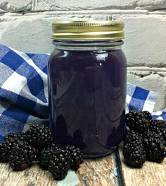 a glass jar filled with blackberries sitting on top of a blue and white checkered table cloth