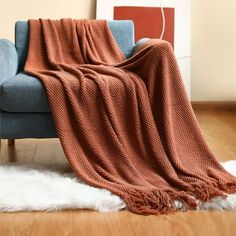 a couch with a blanket on top of it in front of a wall and floor