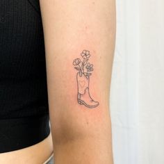 a woman's arm with a small boot and flowers tattoo on the left inner arm