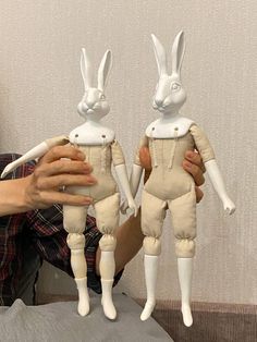 a person holding two white rabbits in their hands