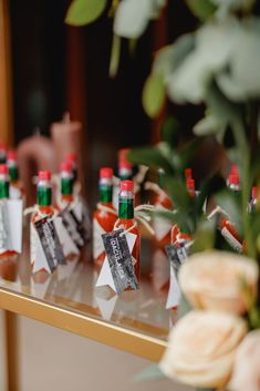 several bottles of hot sauce sitting on top of a table next to flowers and candles