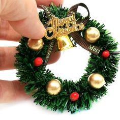 a hand is holding a christmas wreath ornament