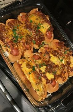 several hot dogs in buns with toppings sitting on top of an oven burner