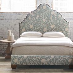 a bed with an ornate headboard and foot board in front of a brick wall