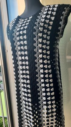 a black and white crocheted dress on display in front of a glass window