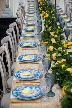 a long table set with blue and yellow plates, flowers and vases on it