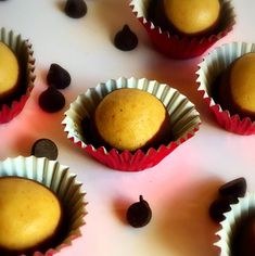 several chocolates in paper cups on a table with some raisins scattered around them