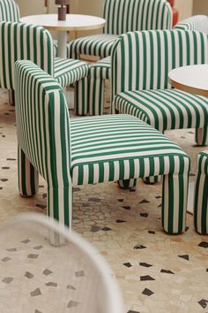 green and white striped chairs sitting on top of a tiled floor next to a table