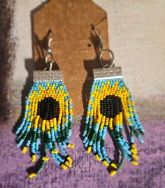 two pairs of beaded earrings with yellow and blue beads on top of purple carpet