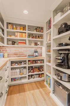 a kitchen with white cabinets and shelves filled with food