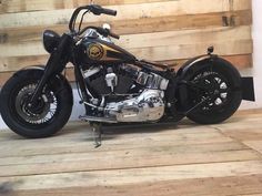 a black and gold motorcycle parked on top of a wooden floor next to a wall