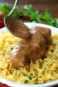 a fork picking up some meatballs with sauce on top of it over pasta noodles