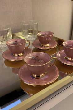 pink tea cups and saucers on display in front of a mirror