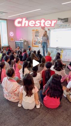 a group of children sitting on the floor in front of a whiteboard with a teacher