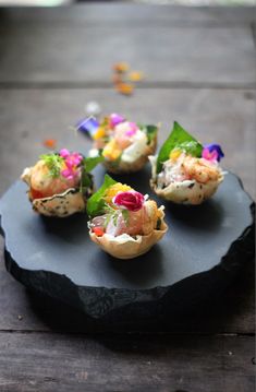 small appetizers are arranged on a black plate