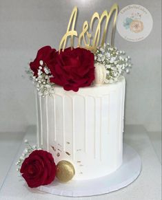 there is a white cake with red flowers on the top and gold letters above it