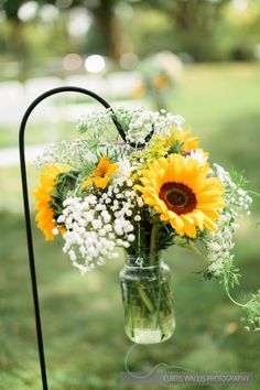 sunflowers and baby's breath in a mason jar on a metal stand