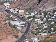 an aerial view of a small town on the side of a hill with cars driving down it