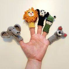 four finger puppets are placed in the palm of a person's hand, which is shaped like animals