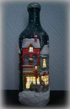 a bottle with a house on it is lit up in the snow and has lights inside