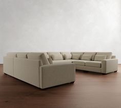 a large sectional couch sitting on top of a wooden floor next to a white wall