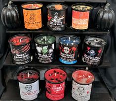 an assortment of halloween flavored ice creams are displayed on a black shelf, with pumpkins in the background