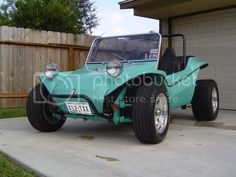 an old style buggy is parked in front of a garage with a wooden fence