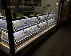 a display case filled with lots of pictures on the side of a building at night