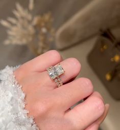 a woman's hand with a diamond ring on top of her finger and the other hand holding an engagement ring