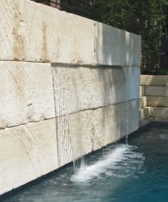 the water is running down the side of the wall and into the swimming pool that's next to it