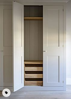 an open closet with wooden drawers and white doors in a room that has light wood flooring