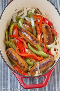 sausages, peppers and onions in a red pan