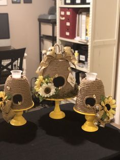 three yellow birdhouses decorated with sunflowers and daisies on a black table