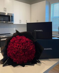 a bouquet of red roses sits on the counter in front of two chanel boxes