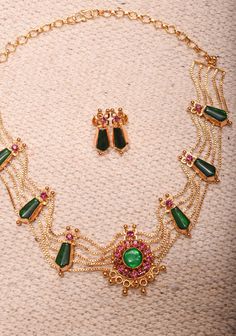 Add a touch of traditional elegance to your collection with this Gold Tone Kerala Style Pink-Green Nagapadam Choker Combo Necklace Set. Featuring a striking choker adorned with intricate nagapadam motifs, this piece beautifully combines rich pink and green hues for a vibrant, eye-catching look. The gold tone enhances its luxurious appeal, making it perfect for weddings, festivals, and special occasions. Accompanied by matching earrings, this set offers a cohesive look that effortlessly elevates any outfit. Embrace the charm of Kerala's artistry and make a stunning statement with this exquisite necklace set Note: This jewelry has no precious metals or stones. *Note: The earrings have thick stems* Note: Some of the pics are close up shots to show detail and may make the product appear larger Exquisite Luxury Earrings For Festive Occasions, Luxury Green Earrings For Festivals, Luxury Festive Choker Jewelry Set, Luxury Statement Choker For Festive Occasions, Traditional Luxury Choker For Festive Occasions, Luxury Gold Blouse Piece With Motifs, Luxury Festive Choker Necklace, Luxury Traditional Festive Choker, Luxury Gold Blazer For Festive Occasions